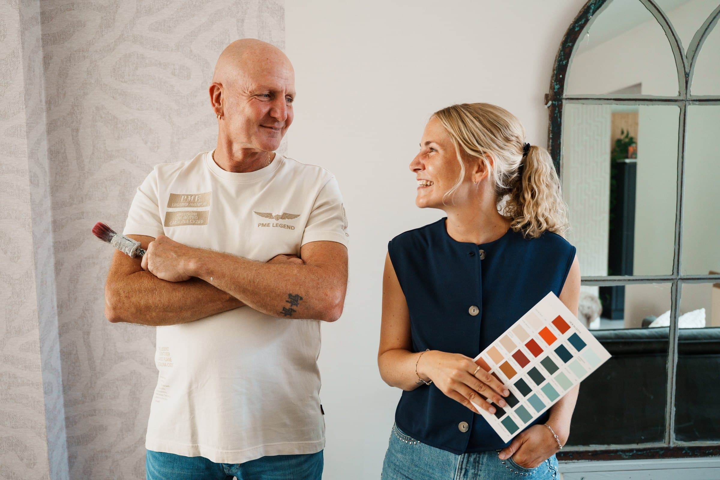 Nikki en haar vader Leen van Fischer schilderwerk kijken elkaar lachend aan